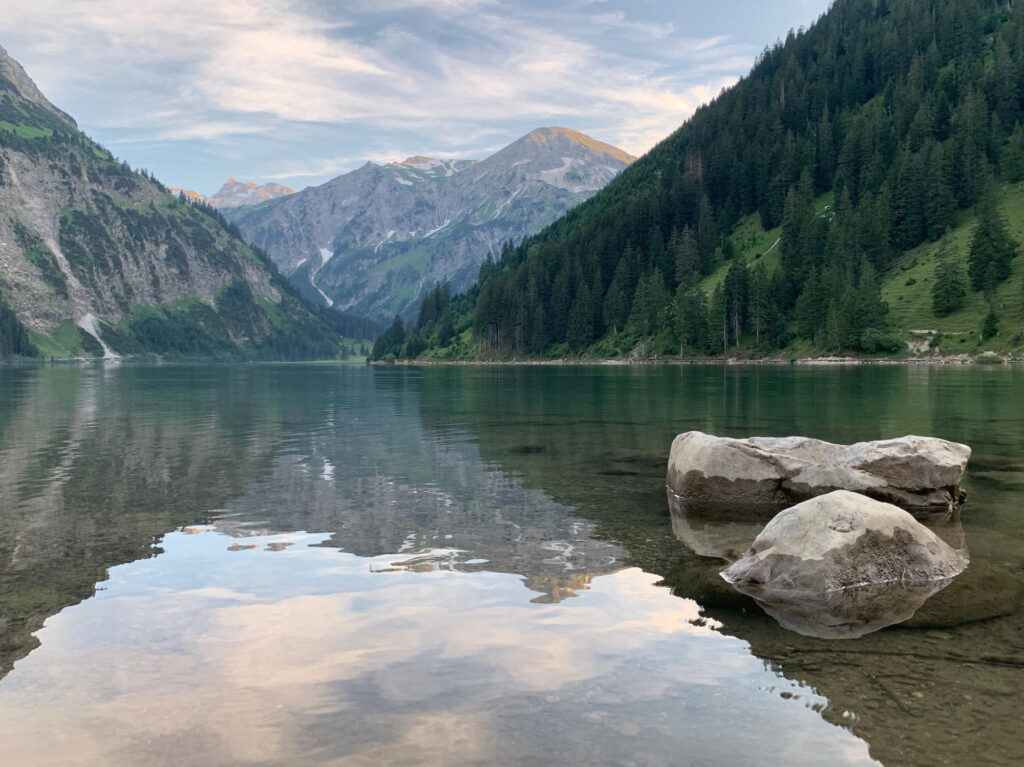 Ruhevoller Bergsee mit reflektierenden Felsen und Bäumen
